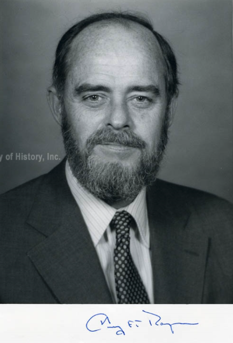A black and white portrait of Harry Thayer, a Caucasian man with a receding hairline and a full beard, wearing a suit and tie. A signature is visible at the bottom.