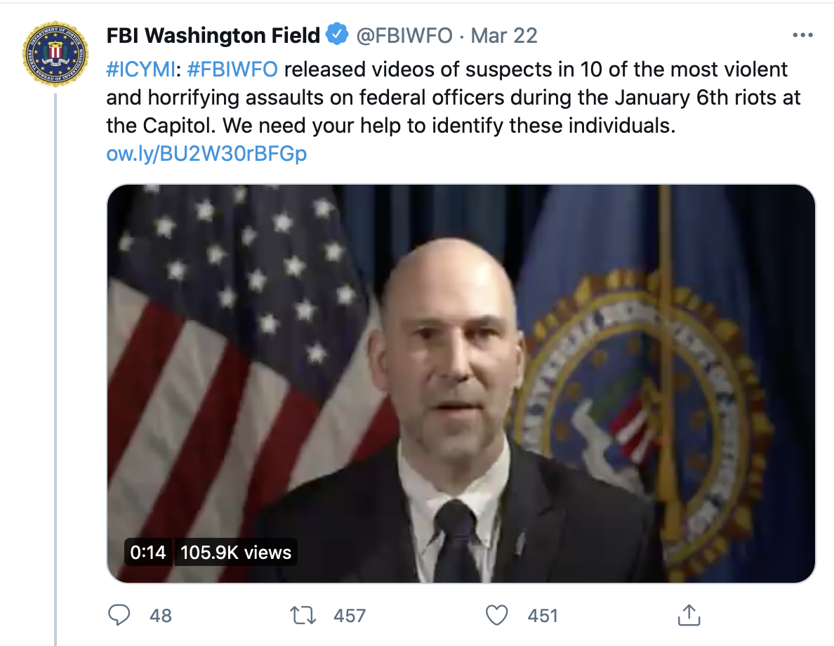 A screenshot of a tweet from the FBI Washington Field Office featuring a bald man in a suit and tie speaking in front of an American flag and an FBI seal. The tweet text discusses identifying suspects from the January 6th Capitol riots.