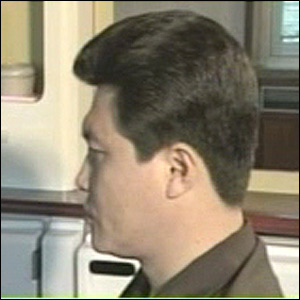 A side profile photograph of an Asian man with thick dark hair, wearing a brown shirt, set against a blurred indoor background.