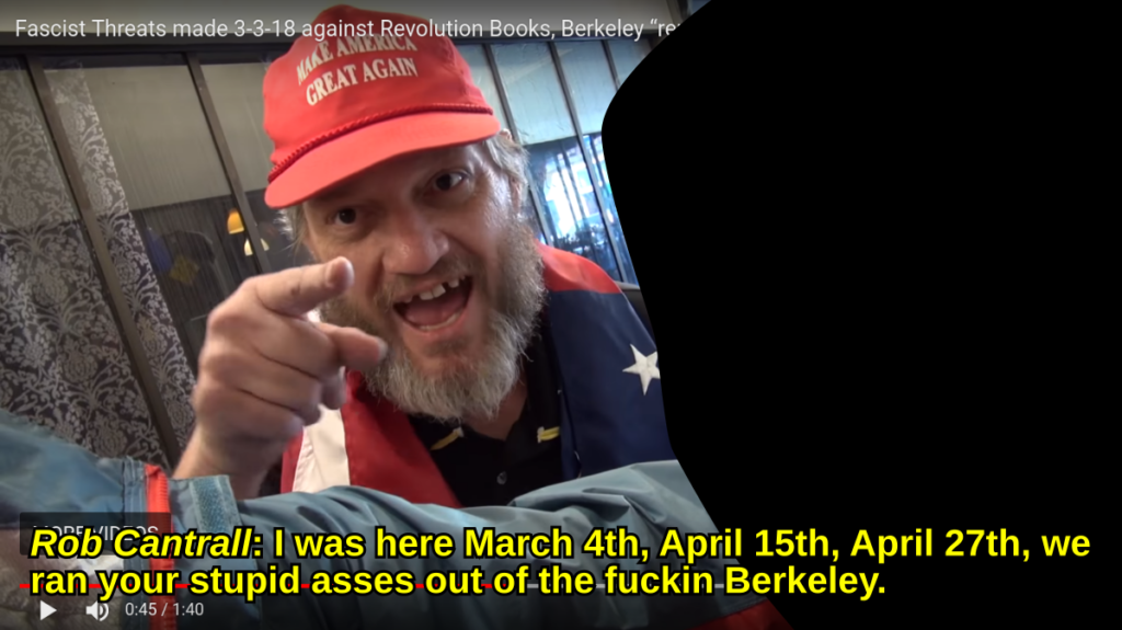 A screenshot of a video featuring a man identified as Rob Cantrall. He is wearing a red 'Make America Great Again' hat and an American flag draped over his shoulders while pointing aggressively at the camera. Yellow subtitles at the bottom quote him making threats regarding Berkeley.