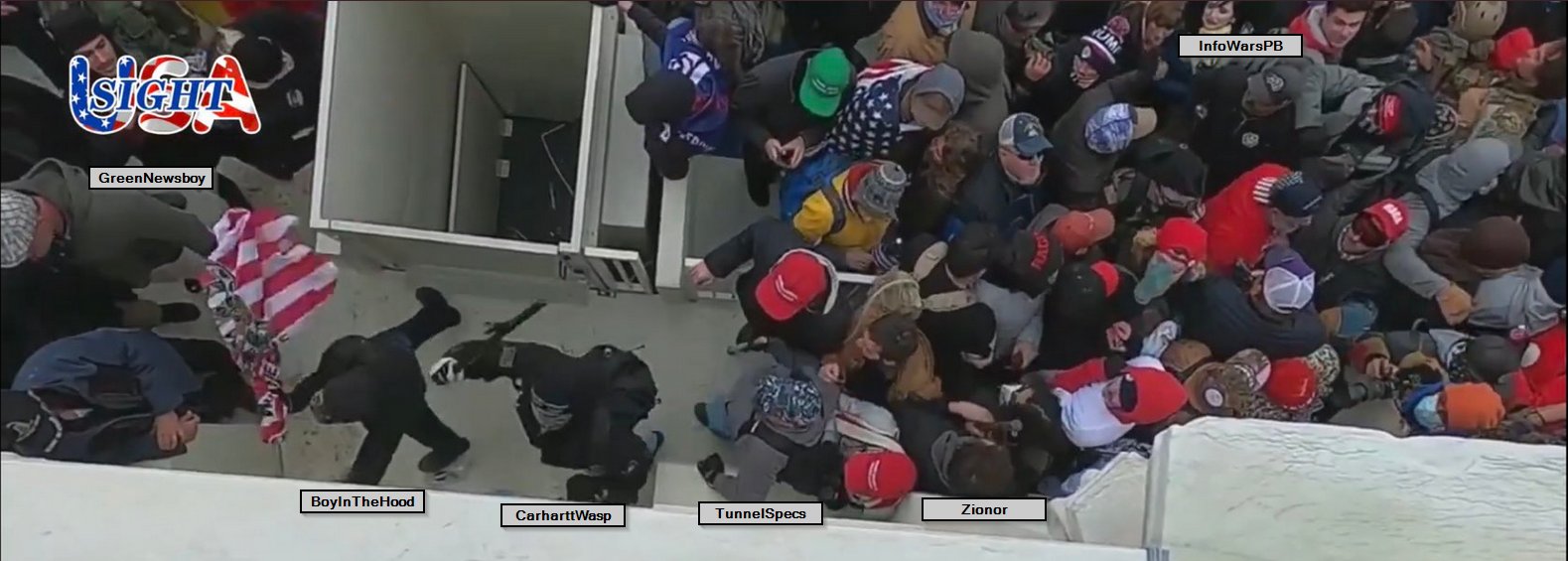 A high-angle photograph showing a dense crowd of individuals, many wearing red hats and tactical gear, during the January 6th Capitol riot. Several people are identified with text labels such as 'GreenNewsboy' and 'InfoWarsPB'.