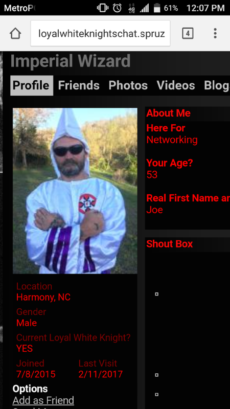 A screenshot of a mobile web browser displaying a profile page for an 'Imperial Wizard' on a website called loyalwhiteknightschat.spruz. The profile features a photo of a man in a white KKK robe with purple stripes and a pointed hood, wearing sunglasses and having a beard. Text on the page indicates the user's name is Joe, location is Harmony, NC, and age is 53.