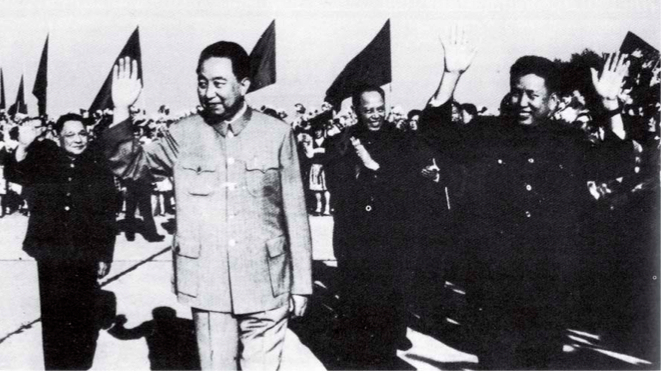 A black and white historical photograph showing Chinese leader Hua Guofeng and Khmer Rouge leader Pol Pot waving to a crowd during a state visit in 1977.
