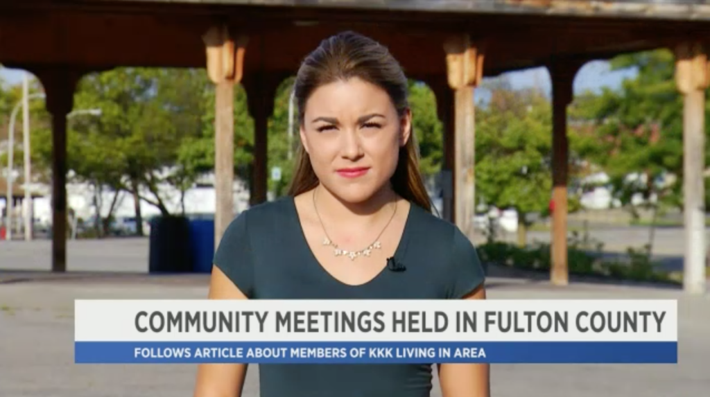 A female news reporter stands in front of a park pavilion. A news graphic at the bottom reads 'COMMUNITY MEETINGS HELD IN FULTON COUNTY' and 'FOLLOWS ARTICLE ABOUT MEMBERS OF KKK LIVING IN AREA'.
