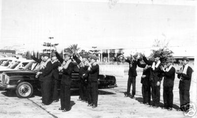 Pol Pot and other Khmer Rouge leaders standing next to Mercedes limousine waiting at Phnom Penh airport to greet arriving VIP delegation