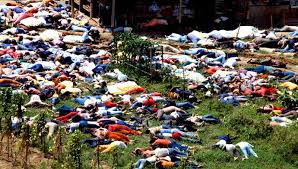 A wide-angle historical photograph showing hundreds of bodies lying on the ground at the Jonestown massacre site in Guyana.
