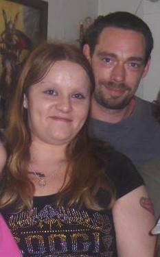 A low-resolution photograph of a Caucasian woman with long reddish-brown hair and a Caucasian man with dark hair and a goatee.