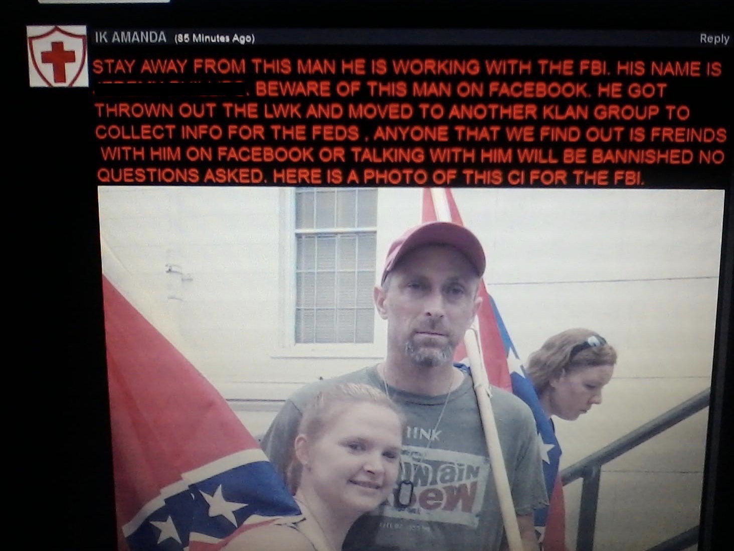 A screenshot of a social media or forum post with red text warning about an alleged FBI informant. Below the text is a photograph of a man with a goatee wearing a red baseball cap and a Mountain Dew t-shirt, holding a Confederate flag next to a woman.
